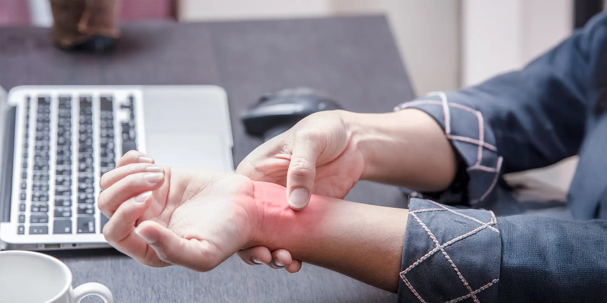 Physical Medicine Columbus GA Person With Carpal Tunnel Pain Person With Carpal Tunnel Pain sitting at a computer desk clutching their wrist