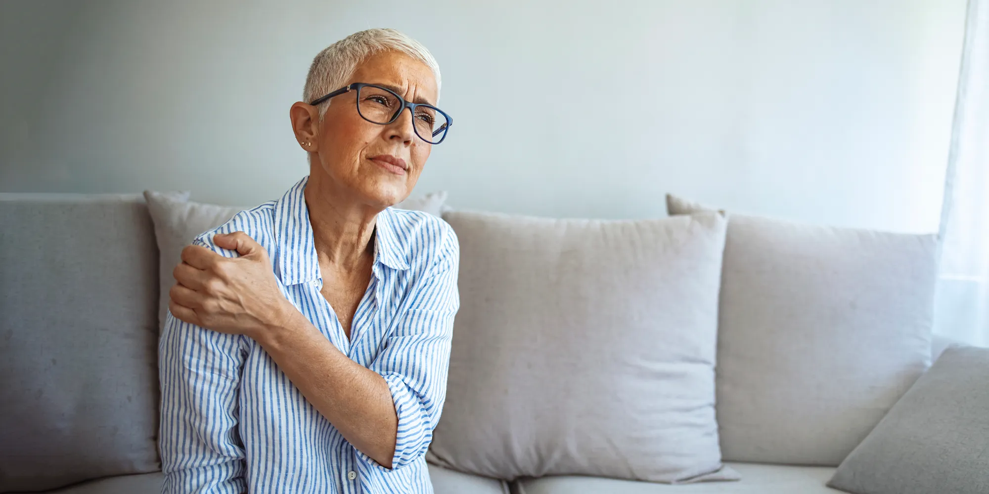 Physical Medicine Columbus GA Woman With Muscle Pain Woman With Muscle Pain holding her arm and looking away in discomfort